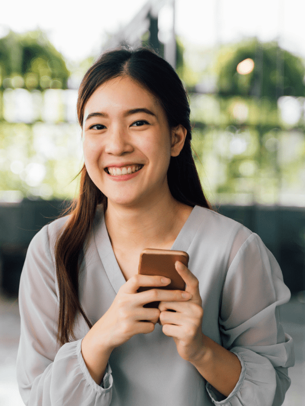 A woman smiling while holding her phone